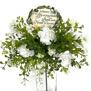 May include: White flowers in a clear vase with a memorial plaque that reads "In Memory of a Life so beautifully Lived, and a Heart so deeply Loved".