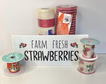 May include: A selection of strawberry-themed craft supplies. Includes rolls of red and natural-coloured mesh ribbon, spools of patterned ribbon, and a white sign that reads "Farm Fresh Strawberries."