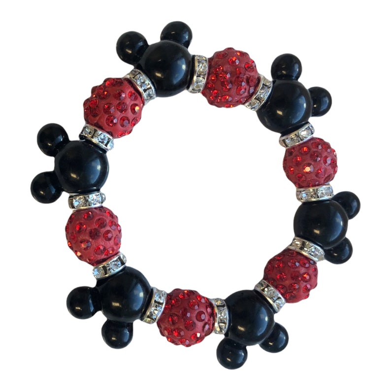 Puede incluir: Un brazalete de cuentas rojas y negras con dijes de cabeza de Mickey Mouse. Las cuentas est&aacute;n cubiertas de brillantes pedrer&iacute;a.