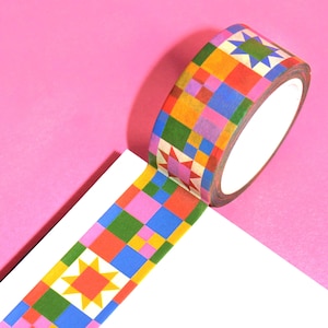 May include: A roll of colorful decorative washi tape with a geometric pattern of squares and starbursts in shades of red, orange, yellow, green, blue, and pink. The tape is partially unrolled, revealing the pattern.