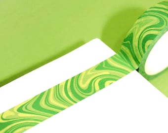May include: Green and yellow washi tape with a marbled pattern. The tape is rolled up and partially unrolled on a white surface.