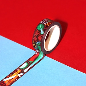 May include: A roll of colorful washi tape with a floral and geometric design. The tape is partially unrolled and is on a red and blue background.
