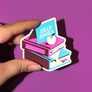 May include: A sticker featuring a stack of colorful books with a blue bookmark and a red apple. The top book has the text "READ BOOKS" on it.