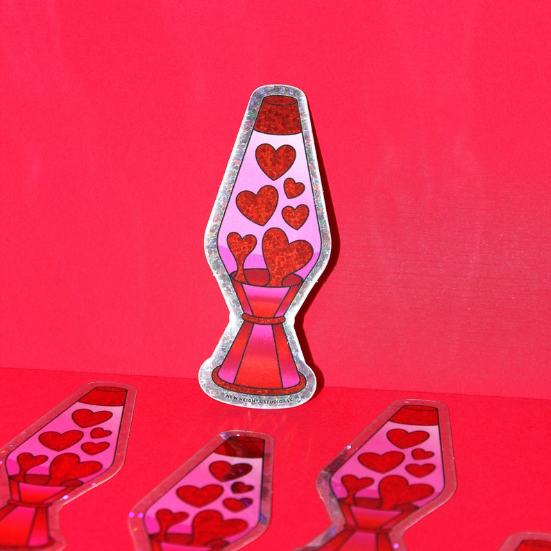 May include: A sticker featuring a lava lamp design with red and pink hearts. The lava lamp has a silver outline and is set against a red background. Several other stickers are scattered around the main image.