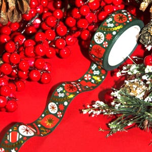 May include: Green and gold washi tape with a Christmas theme. The tape features a repeating pattern of ornaments, holly, candy canes, and stars.