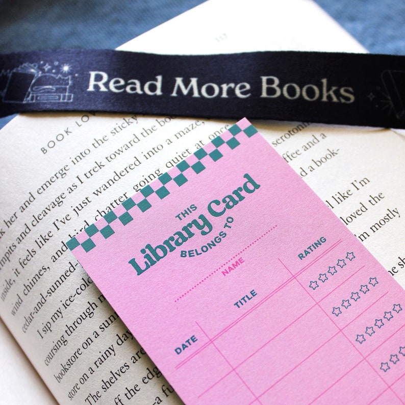 May include: Pink library card with a teal and white checkered pattern at the top. The card has the words "This Library Card Belongs To" printed on it. The card has sections for "Date", "Name", "Title", and "Rating".