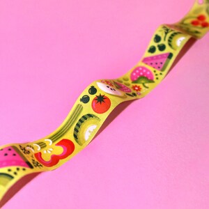 May include: A yellow washi tape with a repeating pattern of colorful fruits and vegetables, including watermelon, strawberries, tomatoes, and cucumbers.