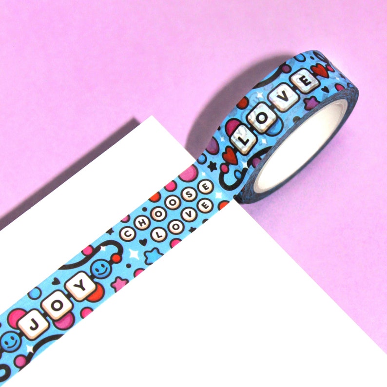 May include: Blue washi tape with a repeating pattern of hearts, stars, smiley faces, and the words "Choose Love", "Joy", and "Love".