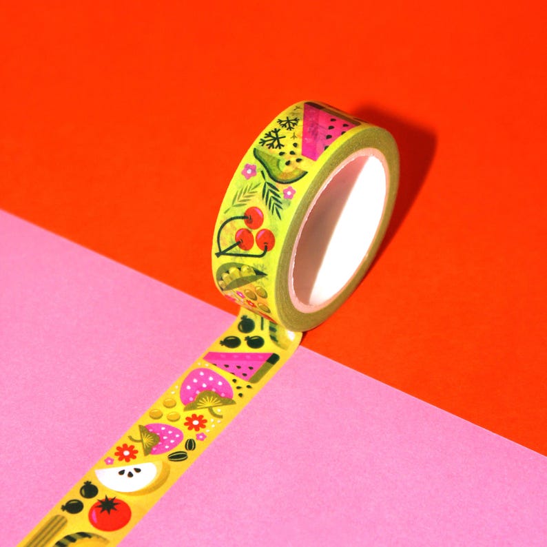 May include: A roll of yellow washi tape with a colorful fruit and vegetable pattern. The tape features watermelon, cherries, avocado, kiwi, and other fruits and vegetables.