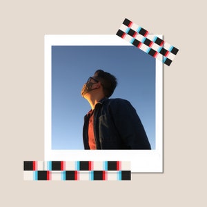 May include: A person wearing a blue denim jacket and a face mask looks up at the sky. The sky is a bright blue with a few clouds.