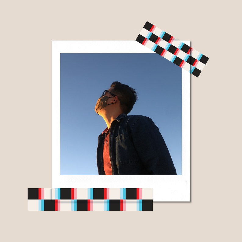 May include: A person wearing a blue denim jacket and a face mask looks up at the sky. The sky is a bright blue with a few clouds.