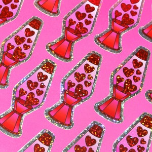 May include: A pattern of stickers featuring a lava lamp design with red glitter hearts on a pink background. The lava lamps are red and pink with a silver glitter border. The hearts are different sizes.