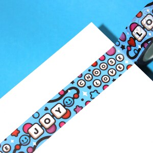 May include: A blue and white washi tape with a repeating pattern of colorful circles, stars, hearts, and smiley faces. The tape features the words "Choose Love" and "Joy" in white letters.