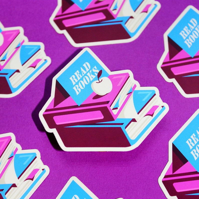 May include: A set of five stickers featuring a stack of books with a blue banner that says "Read Books" and a red apple on top. The stickers are on a purple background.