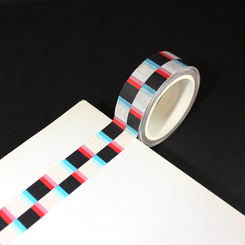 May include: A roll of washi tape with a black, white, red, and blue checkered pattern.