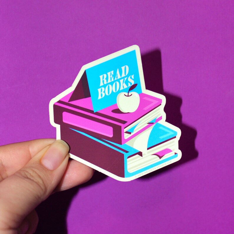 May include: A sticker with a stack of colorful books, an apple, and the text "READ BOOKS".