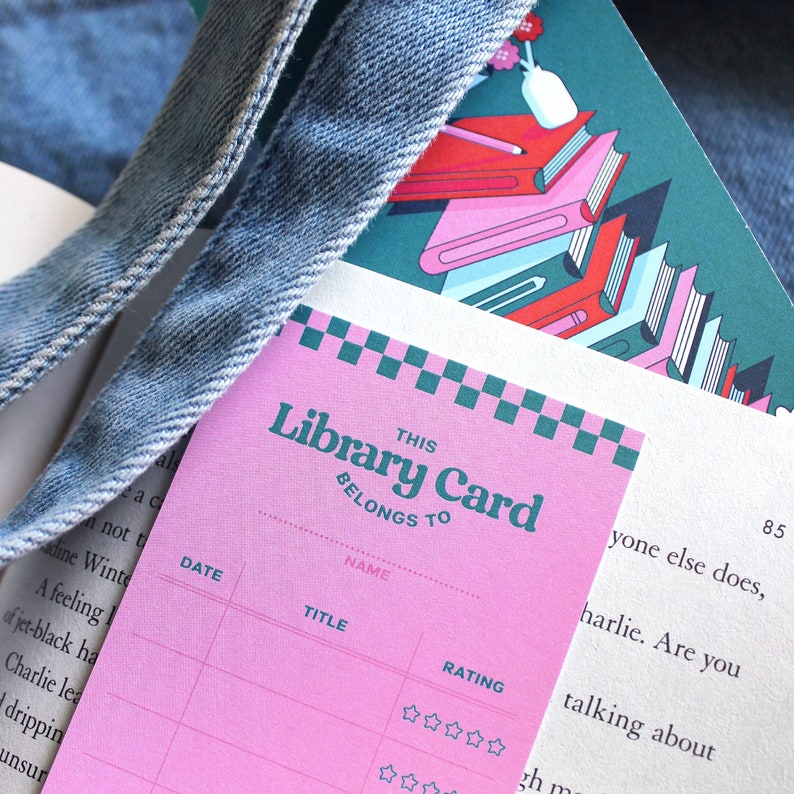 May include: Pink library card with a checkered border and the text "THIS Library Card BELONGS TO". The card has sections for "NAME", "DATE", "TITLE", and "RATING". The rating section has five stars.