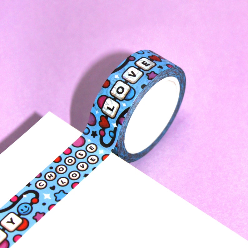 May include: A roll of blue washi tape with a repeating pattern of hearts, stars, and the words "Choose Love" and "Love".