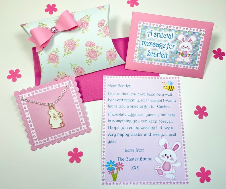 May include: A pink card with a message from the Easter Bunny to Scarlett. The card includes a bee, flowers, and a bunny illustration. A pink envelope with a white floral pattern and a pink bow is included. A small pink card with a silver chain and a bunny charm is also included.