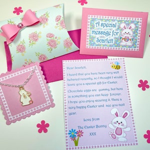 May include: A pink envelope with a white bunny and the text "A special message for Scarlett". A pink card with a bee and the text "Dear Scarlett, I heard that you have been very well behaved recently, so I thought I would leave you a special gift for Easter. Chocolate eggs are yummy, but here is something you can keep forever. I hope you enjoy wearing it. Have a very happy Easter and see you next year. Love from The Easter Bunny XXX". A pink card with a white bunny and a silver necklace with a white bunny charm.