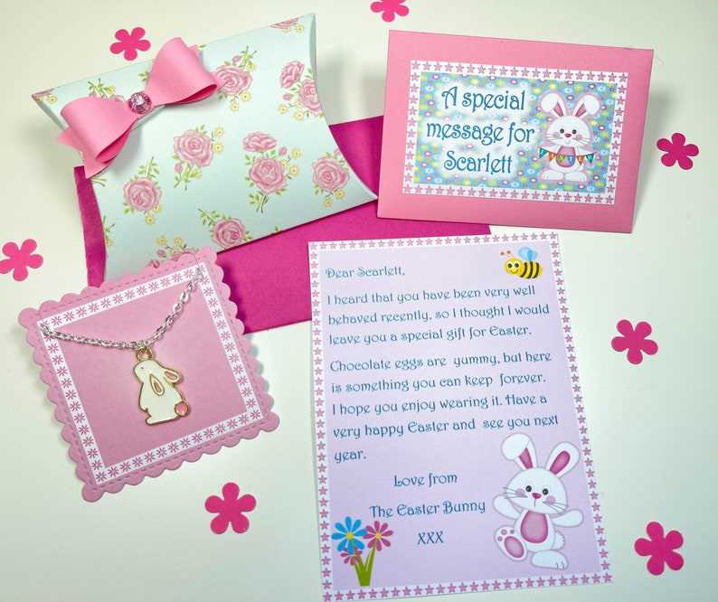May include: A pink envelope with a white bunny and the text "A special message for Scarlett". A pink card with a bee and the text "Dear Scarlett, I heard that you have been very well behaved recently, so I thought I would leave you a special gift for Easter. Chocolate eggs are yummy, but here is something you can keep forever. I hope you enjoy wearing it. Have a very happy Easter and see you next year. Love from The Easter Bunny XXX". A pink card with a white bunny and a silver necklace with a white bunny charm.