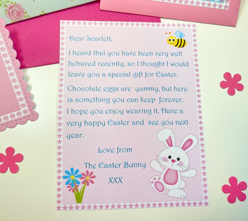 May include: A pink and blue card with a white bunny and a bee illustration. The card has a message for Scarlett, wishing her a happy Easter. The text reads: "Dear Scarlett, I heard that you have been very well behaved recently, so I thought I would leave you a special gift for Easter. Chocolate eggs are yummy, but here is something you can keep forever. I hope you enjoy wearing it. Have a very happy Easter and see you next year. Love from The Easter Bunny XXX"