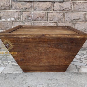 May include: A dark brown wooden coffee table with a rectangular top and a unique, angled design. The table has a rustic, distressed finish and is made of solid wood.