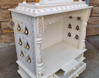 May include: White wooden temple with gold accents and decorative carvings. The temple has a small drawer and a shelf inside. There are small bells hanging from the top of the temple.