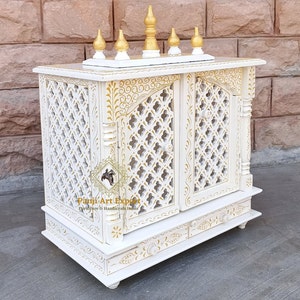 Puede incluir: Templo de madera blanco con intrincados tallados dorados y dos puertas. El templo tiene un peque&ntilde;o estante en la parte superior y dos cajones en la parte inferior. El templo est&aacute; decorado con un dise&ntilde;o floral.