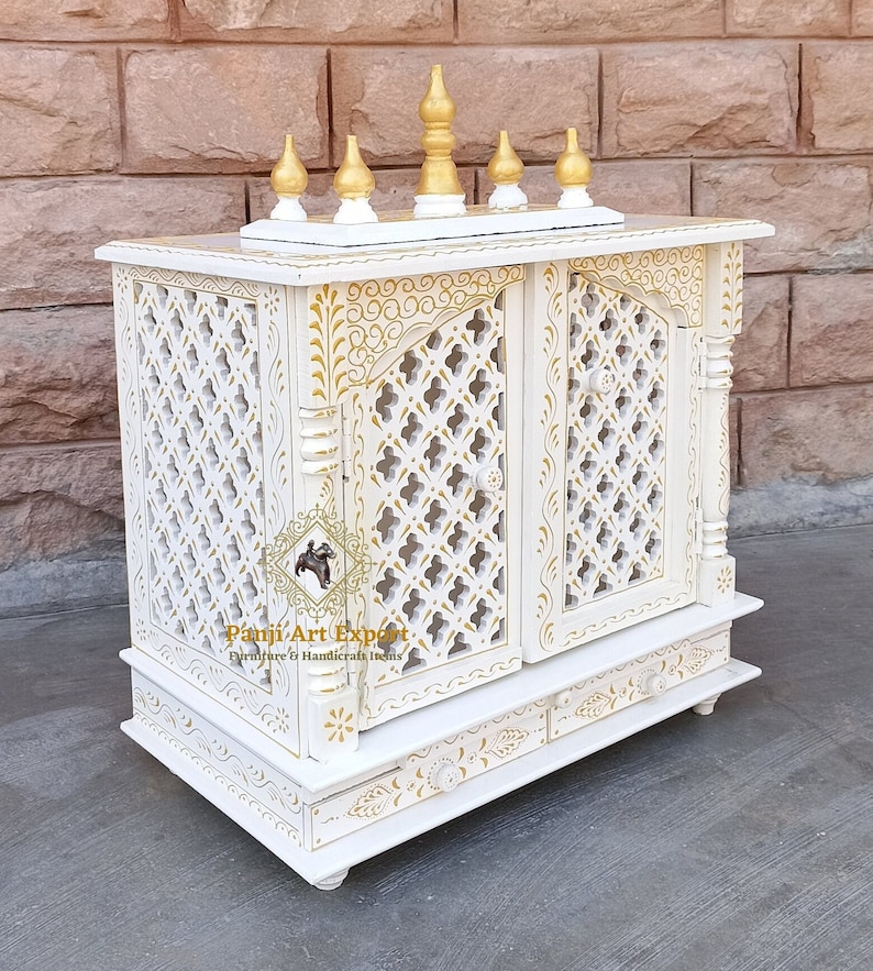 Puede incluir: Templo de madera blanco con intrincados tallados dorados y dos puertas. El templo tiene un peque&ntilde;o estante en la parte superior y dos cajones en la parte inferior. El templo est&aacute; decorado con un dise&ntilde;o floral.