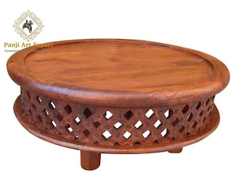 May include: A round, wooden coffee table with a dark brown finish. The table features a decorative, openwork design around the sides and rests on three short legs. The top surface is smooth and circular. The text "Panji Art Export" is visible.