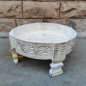May include: White wooden tray with intricate carved details and three legs. The tray is round and has a raised edge.