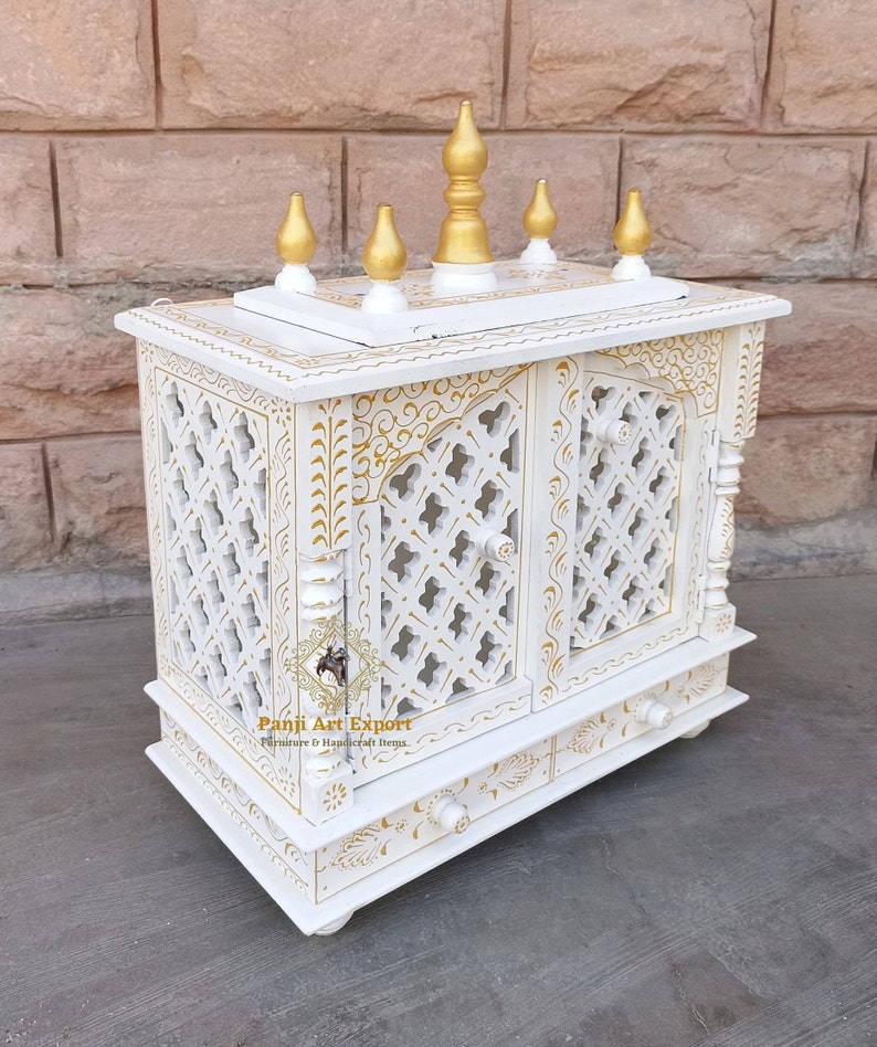 Puede incluir: Templo de madera blanco con detalles dorados y tallas intrincadas. El templo tiene dos puertas y un caj&oacute;n. Est&aacute; decorado con un dise&ntilde;o tradicional indio.