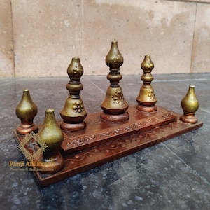 Op de afbeelding: Een houten standaard met vijf decoratieve gouden en bruine toppen. De standaard heeft een gesneden ontwerp en is perfect om kleine voorwerpen op te tentoonstellen.