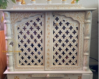 May include: White wooden temple with gold accents and intricate carvings. The temple has two doors with a lattice design and a drawer at the bottom.