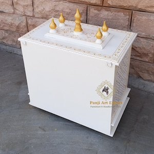 Puede incluir: Templo de madera blanco con detalles dorados y tallas decorativas. La parte superior del templo tiene cinco remates dorados. El templo est&aacute; sobre una superficie blanca. "Panji Art Export" est&aacute; impreso en el lateral del templo.