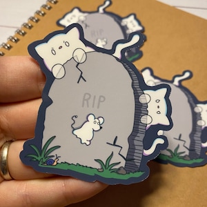 May include: A white cat with blue eyes is peeking over a gray tombstone with the word "RIP" on it. A white mouse is floating next to the cat. There is a snail on the ground below the tombstone.