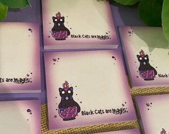 May include: Purple sticky notes with a black cat illustration inside a cauldron. The text "Black Cats are magic" is printed on the notes.