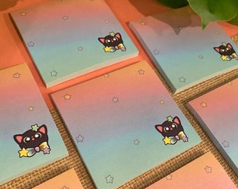 May include: A set of pastel rainbow gradient sticky notes with a black cat illustration holding a star. The notes have a subtle sparkle effect and are perfect for adding a touch of whimsy to your planner or journal.
