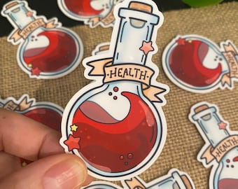 May include: A red potion bottle sticker with a white label that says "HEALTH" in a banner. The bottle is filled with a red liquid and has a cork stopper. There are stars on the bottle and label.