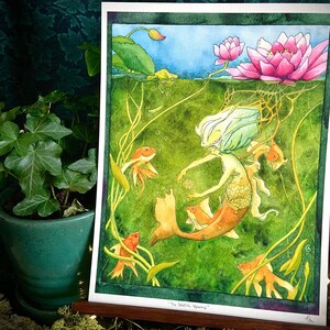 Puede incluir: Pintura acuarela de una sirena con cabello largo rubio y cola verde, rodeada de peces dorados. La sirena está extendiendo la mano a los peces. El fondo es un estanque con nenúfares y flores.