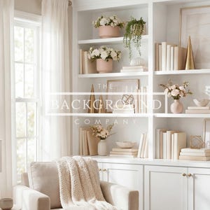 Könnte beinhalten: Ein helles, luftiges Wohnzimmer mit weißen Einbauregalen, die mit Büchern, Vasen und dekorativen Objekten gefüllt sind. Die Regale sind mit Blumenarrangements in rosa Töpfen und gerahmten Kunstwerken geschmückt. Ein neutraler Sessel mit einem cremefarbenen Überwurf und eine Lampe vervollständigen die Szene.