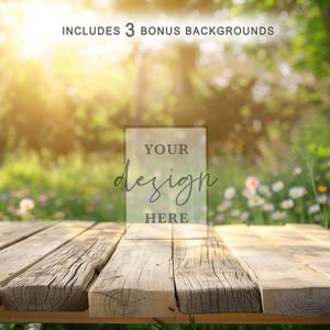 May include: A rustic wooden table with a clear acrylic sign that reads "YOUR design HERE." The background features a blurred, sunlit garden with green foliage and white flowers. The text "INCLUDES 3 BONUS BACKGROUNDS" is at the top.