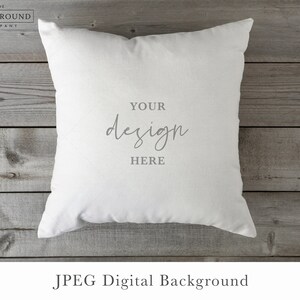 May include: A square white throw pillow featuring the centered gray text "YOUR design HERE" in a combination of block and script fonts. The pillow has a smooth, solid-colored fabric surface and is presented as a digital mockup template.