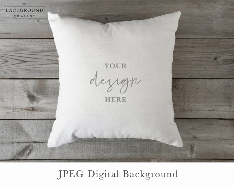 May include: A square white throw pillow featuring the centered gray text "YOUR design HERE" in a combination of block and script fonts. The pillow has a smooth, solid-colored fabric surface and is presented as a digital mockup template.