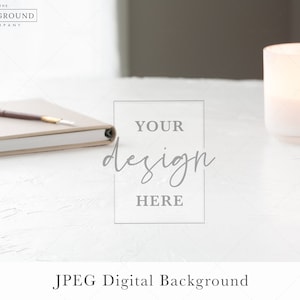 May include: A white table with a closed notebook, a brown pen, and a white candle in a glass jar. The text "YOUR design HERE" is written on the table.