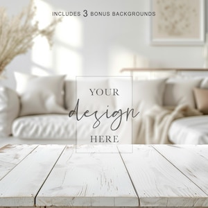 Könnte beinhalten: Ein rustikaler weißer Holztisch im Vordergrund mit dem Text "YOUR design HERE" überlagert. Der Hintergrund zeigt eine verschwommene Wohnzene mit einem weißen Sofa, Kissen und dekorativen Elementen. Das Bild enthält 3 Bonus-Hintergründe.