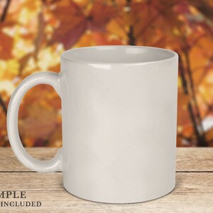 May include: A plain white ceramic mug with a smooth, glossy finish and a curved handle on the left side. The mug is positioned upright, featuring a cylindrical body and a wide opening at the top, presented as a blank vessel for customization.