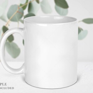 May include: A plain white ceramic mug with a smooth, glossy finish and a curved handle on the left side. The mug features a cylindrical body with a wide opening at the top and a flat base, presented as a blank vessel for customization or display.