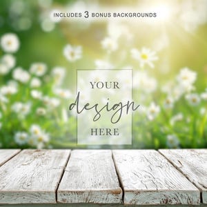 May include: A white weathered wooden surface with a rectangular frame containing the text YOUR design HERE, positioned in front of a blurred field of white daisies and green grass, with text at the top stating INCLUDES 3 BONUS BACKGROUNDS.